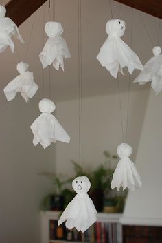 some white paper dolls hanging from strings in the shape of ghost's on a string