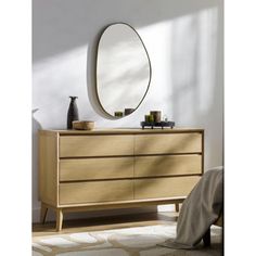 a wooden dresser with a round mirror above it