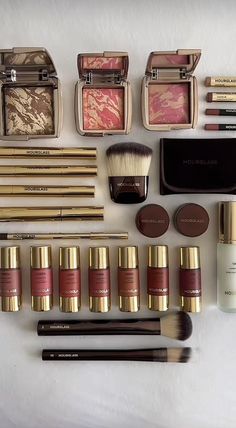 the contents of an assortment of cosmetics and makeup brushes are laid out on a white surface