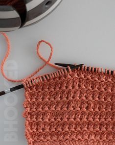 an orange crocheted piece of cloth next to a pair of scissors