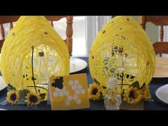 two yellow bird cages sitting on top of a table next to plates and vases