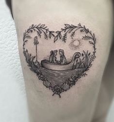 a woman's thigh with a heart shaped tattoo on it and two people in a boat