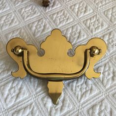 a close up of a gold door handle on a white bed sheet with flowers in the background