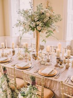 the table is set with silverware and pink flowers in a tall vase on top