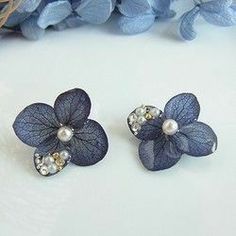 two blue flower earrings with pearls on them