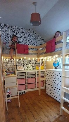 two children sitting on top of bunk beds in a room with wooden floors and walls