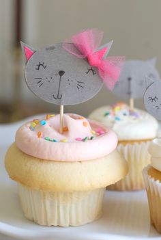 cupcakes with cat toppers on them sitting on a plate