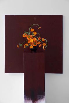 an abstract painting with orange flowers in a black vase on top of a wooden block