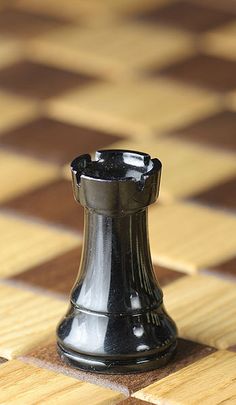 a black vase sitting on top of a checkered wooden tablecloth covered in brown and white tiles