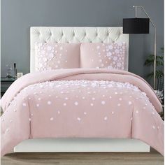 a bed with pink comforter and pillows