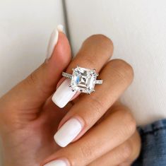 a woman's hand with white manicured nails and an engagement ring on her finger