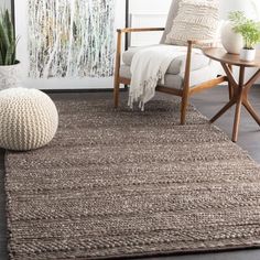 a living room area with a chair, rug and potted plant on the floor