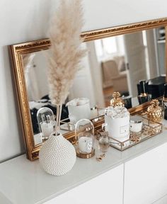 a white dresser topped with a mirror and lots of candles