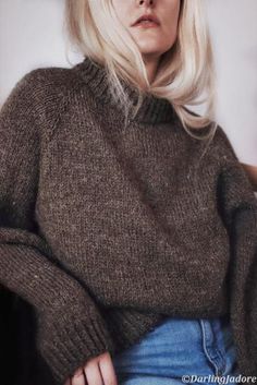 a woman with blonde hair wearing a brown sweater and jeans