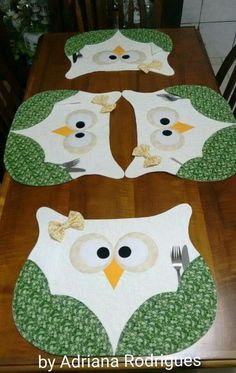 four owls sitting on top of a wooden table with plates and forks in front of them