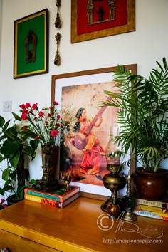 a wooden table topped with lots of potted plants next to pictures on the wall