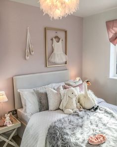 two stuffed animals sit on the bed in this girls's pink and white bedroom