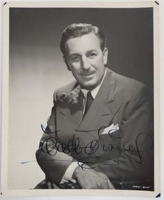 an autographed photograph of a man in a suit and tie with his arms crossed