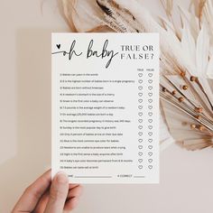 a person holding up a baby shower checklist with feathers around it and the words, true or false?