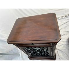 an old fashioned wooden table with intricate carvings on the top and bottom, sitting on a sheet covered ground