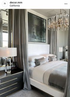 a bedroom with a bed, mirror and chandelier