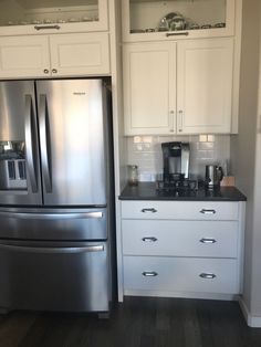 a stainless steel refrigerator freezer sitting next to a white kitchen cabinet with black counter tops