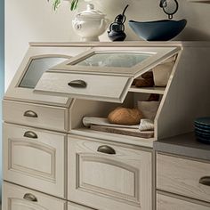 a white dresser with drawers and plates on top of it in front of a window