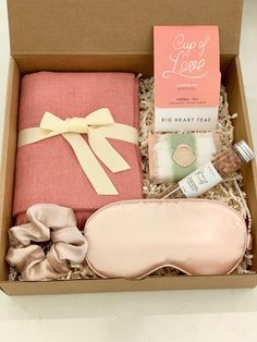 an open box with some items in it on a white table and a pink pillow