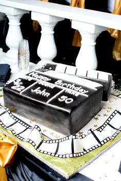 a black and white cake sitting on top of a table next to a gold ribbon