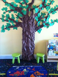 a child's playroom with green chairs and a tree made out of paper