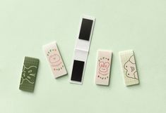 four small erasers in different designs on a green surface