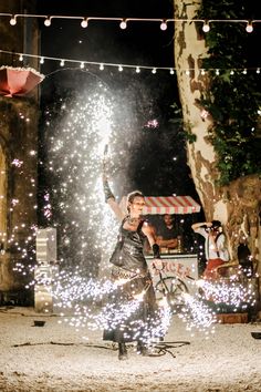 a woman standing on top of a street next to a tree filled with sparkles