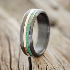 a wedding band with green and white wood inlays on an old wooden surface