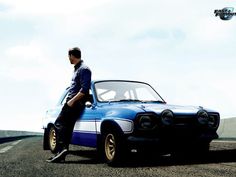 a man leaning on the hood of a blue car