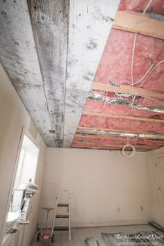 an unfinished room with red and white paint on the walls, wood beams and ceiling