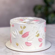 a white cake with pink and gold decorations