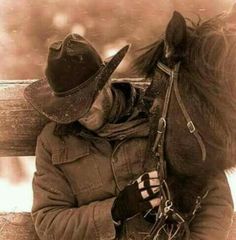 a person sitting on a bench next to a horse wearing a cowboy hat and jacket