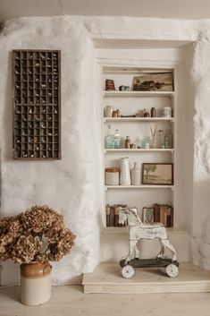 a room with white walls and shelves filled with books, vases and other items