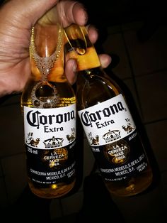 two bottles of corona beer being held by someone