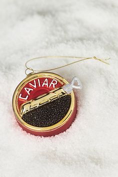 a red and gold pendant with the word lavar on it sitting in some snow