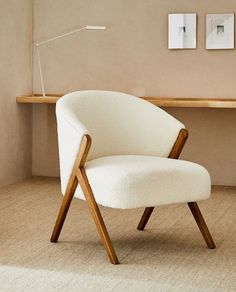 a white chair sitting in front of a wooden desk with two pictures on the wall