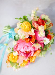 a bridal bouquet with colorful flowers and blue ribbon