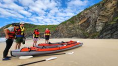 three people standing on the beach next to an inflatable raft