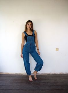 A killer pair of blue denim overalls nicely broken in, and great fade, with adjustable straps and a low back. high waist, front zipper, orange stitching, pockets, and a 'Pick a Pocket' logo on the back pocket. The harem-style straight legs have elastic hems. These rare overalls are in good vintage condition, aside from minor signs of wear, including a small amber stain on the back panel (see attached video). Clean and ready to wear.  **Model is 5'7", and size S for reference   Approximate size: Hippie Jeans, Overalls Vintage, Cotton Jumpsuit, Pocket Logo, Bib Overalls, Overalls Women, Denim Overalls, Blue Jean, Vintage 70s