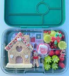 a plastic container filled with assorted food items and a small house shaped cookie in it