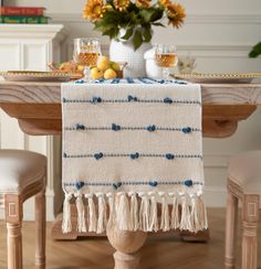 a table topped with a white and blue blanket next to a vase filled with flowers