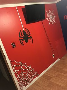 there is a red wall with spider webs on it and two televisions mounted to the wall