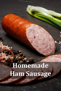 ham sausage with spices and seasoning next to it on a black surface, surrounded by vegetables