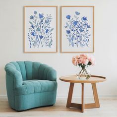 two blue chairs sitting next to each other near a table with flowers in vases on it