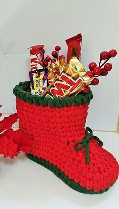 a knitted christmas stocking with candy bars and candies in it, sitting on a white surface